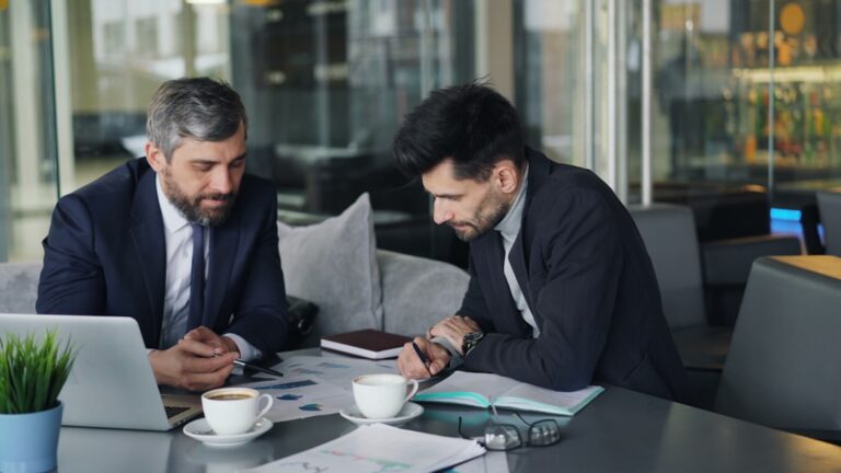 Dois Homens Sentados Em Uma Mesa Trabalhando Em Um Laptop biciz2eSkiA