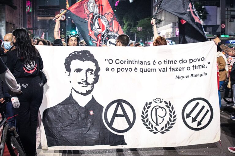 Um Grupo De Pessoas Segurando Uma Faixa Com Uma Foto De Um Homem EGf_s5kZFZU