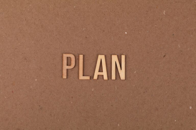 Wooden letters spelling 'PLAN' on a textured cardboard background with ample copy space.
