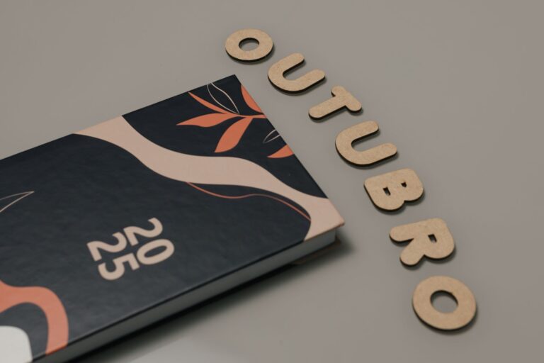 Minimalist flat lay featuring a 2025 planner and cut-out letters spelling 'OUTUBRO'.