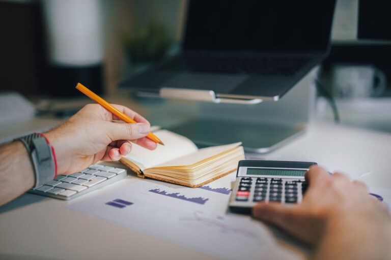 Uma Pessoa Sentada Em Uma Mesa Com Uma Calculadora E Um Caderno LNnmSumlwO4