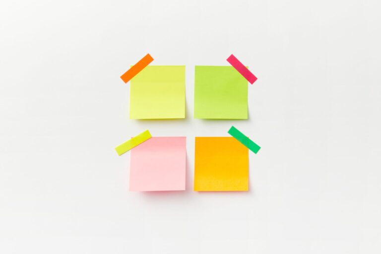 Four colorful sticky notes on white backdrop with vibrant tape. Perfect for office or organizational themes.