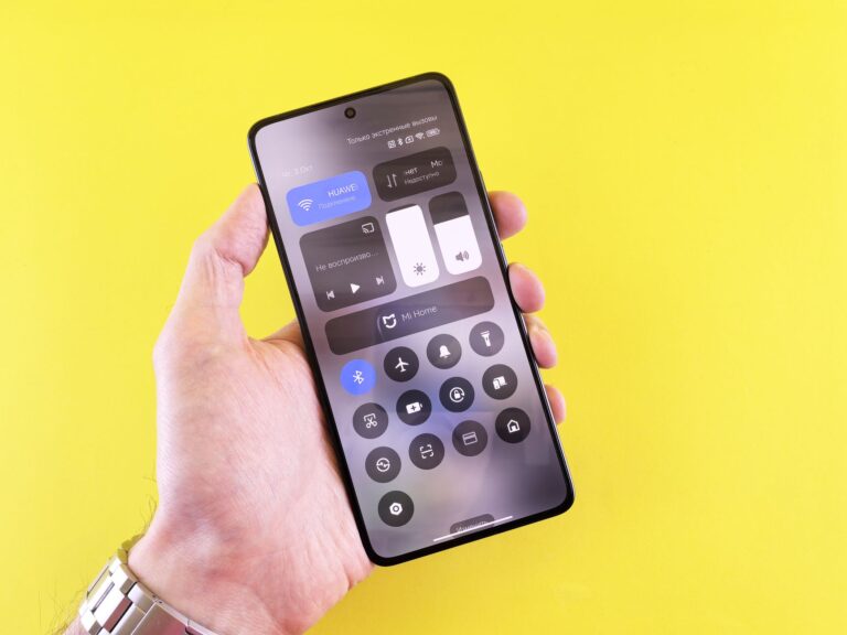 Close-up of a hand holding a smartphone against a vibrant yellow backdrop.