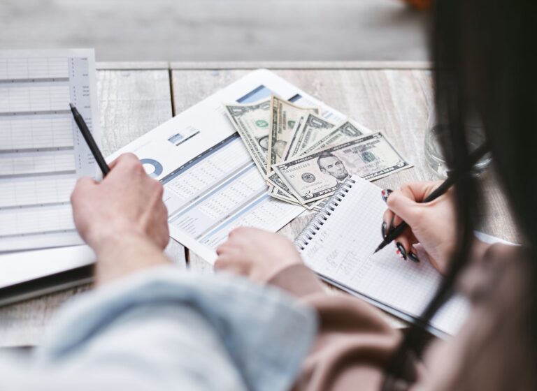 Two people working on financial documents and dollar bills for budgeting.
