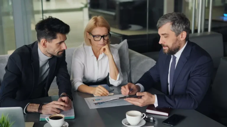 Um Grupo De Pessoas Sentadas Ao Redor De Uma Mesa LS5dCL0NkhE
