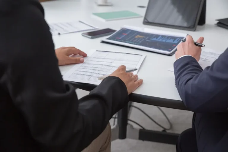 Close-up of professionals reviewing documents in an office setting, focused on analytics.