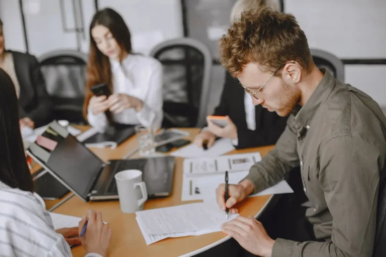 Business professionals engaged in a corporate meeting, emphasizing document signing and collaboration.