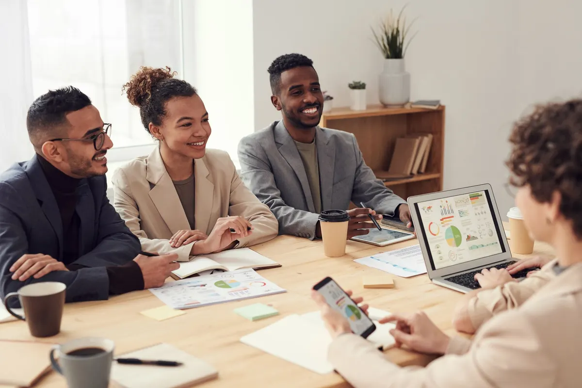 Young professionals discussing work at a conference table with technology and documents.
